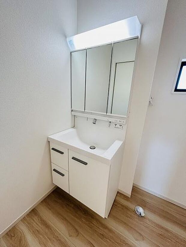 清潔感のあるデザインの洗面台です。鏡の収納スペースが豊富で日常の使い勝手が良好です。床材との調和が取れた明るい空間になっています。シンプルな設計でお手入れもしやすい仕様です。