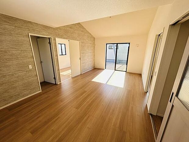 リビングは明るい採光が特徴です。木目調の床が空間に温かみを感じさせます。天井が高く開放感があります。隣室へのアクセスも便利な間取りです。壁紙のアクセントも魅力の一つです。