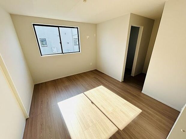 大きな窓から光が差し込む明るい寝室です。すっきりとした内装が印象的です。床材は落ち着いた色合いで空間がまとまりやすいです。収納スペースへのアクセスも便利です。