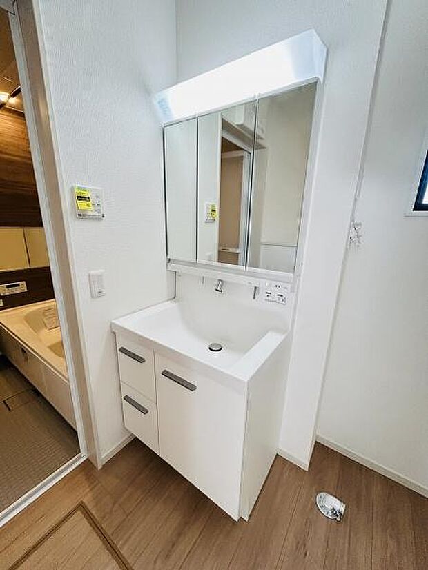 明るい照明が特徴的な洗面台です。収納スペースも充実しており日常使いに便利な設計です。隣室との動線もスムーズで使い勝手が良い空間です。清潔感のある内装が魅力です。