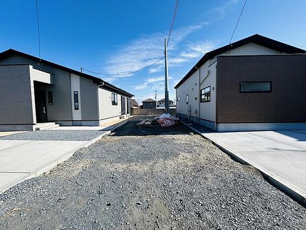 現地写真には開放感ある空間が広がっており隣接する建物との距離感も十分に確保されています。前面道路は幅が広く車の出入りにもゆとりがあります。晴れ渡る空の下で周囲の環境もすっきりとした印象です。