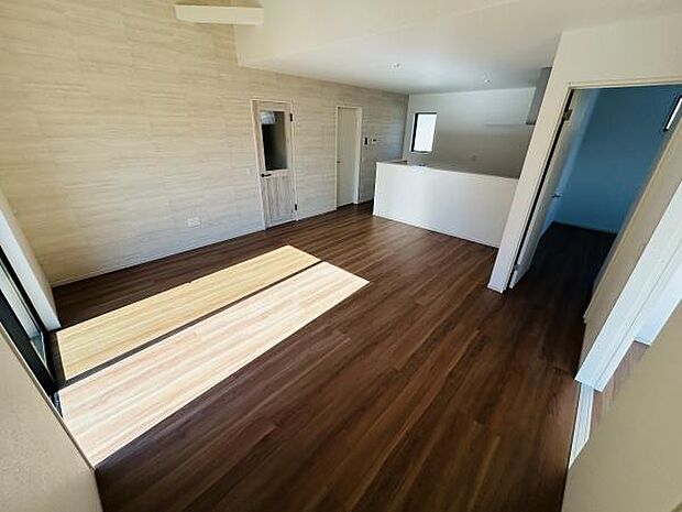 リビングは開放感のある空間が広がっています。大きな窓から光がたっぷり入ります。床材の色合いが落ち着いた雰囲気を演出しています。キッチンとのつながりもスムーズです。