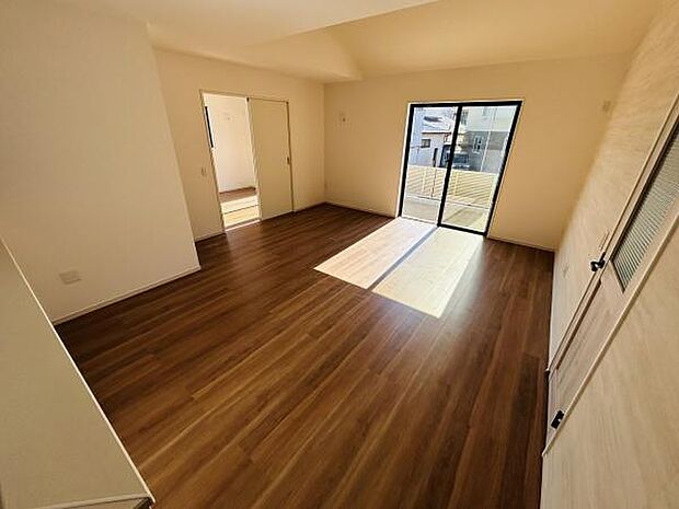 明るい日差しが差し込むリビングです。スライドドアを開けることで空間を自由に使えます。木目調のフローリングが落ち着いた雰囲気を演出しています。大きな窓が開放感を演出しています。