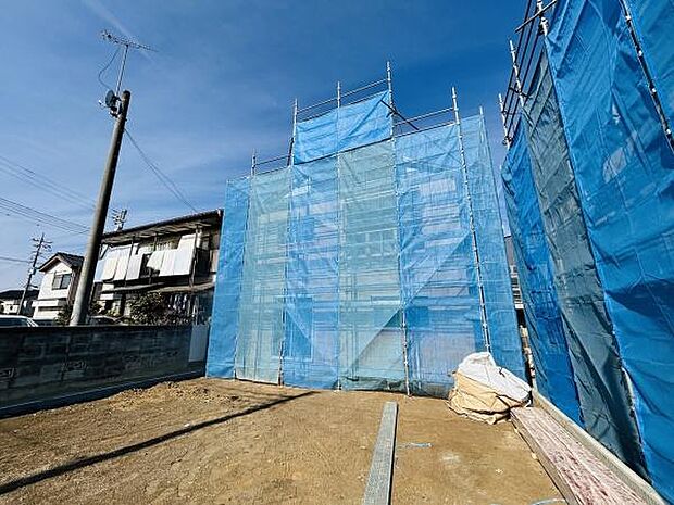 建築中の様子がしっかりと確認できる現場写真です。ブルーシートで丁寧に覆われており作業の進捗がうかがえます。周囲には落ち着いた住宅街が広がっています。土地の広さも感じられる一枚です。