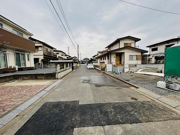 静かな住宅街に位置する前面道路含む現地写真です。道路幅もあり車の出入りがしやすい点が特徴です。周囲には新築や既存住宅が立ち並び現地の様子がわかりやすい環境です。
