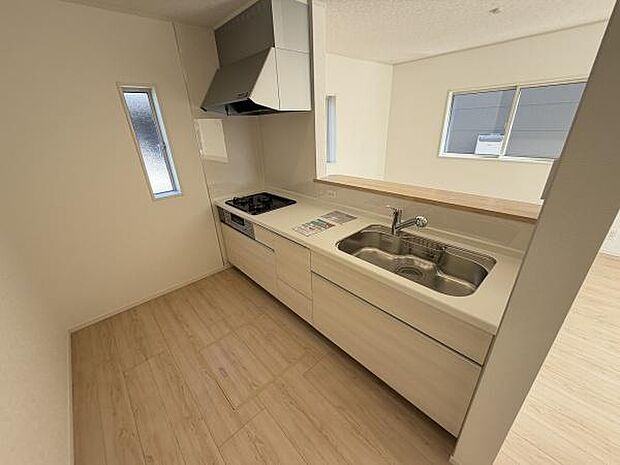 シンプルで使いやすいキッチンです。作業がしやすいカウンター付きです。換気扇やシンクコンロの配置も効率的です。大きな窓から光が差し込み明るい空間を演出しています。収納スペースも充実しています。