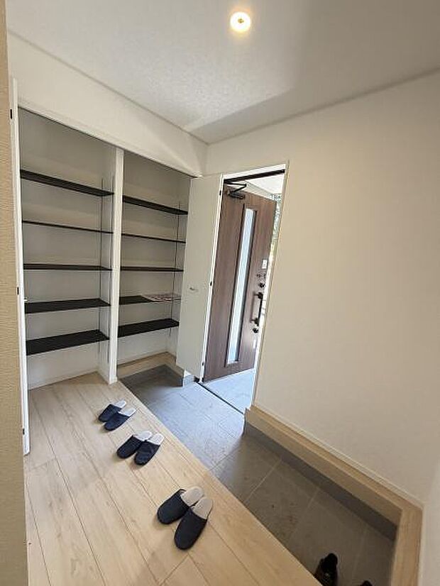 玄関は広々とした空間が広がり収納棚も充実しています。シンプルなデザインで清潔感があります。明るい採光が印象的で快適に使用できます。ゆったりとした印象を与える玄関スペースです。