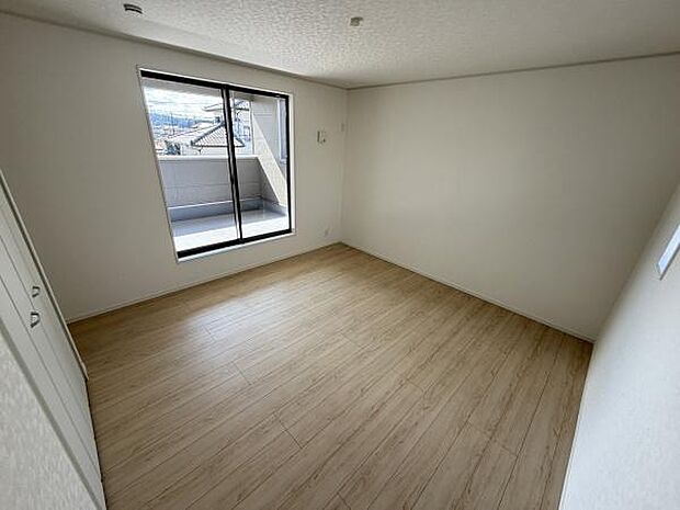 シンプルなデザインの寝室で快適な空間が広がっています。大きな窓から自然光がたっぷり差し込みます。収納スペースも備わっています。床材が温かみを感じさせます。バルコニーへのアクセスも便利です。