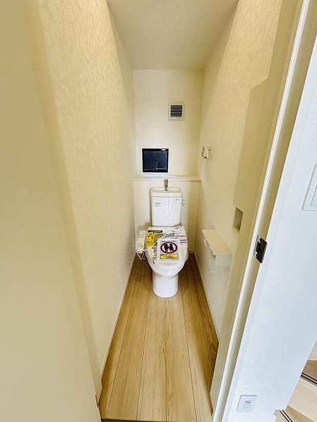 ナチュラルな木目調のフローリングが印象的なトイレです。すっきりとした空間で清潔感があります。収納スペースもしっかり確保されています。換気設備も設置されており快適にお使いいただけます。