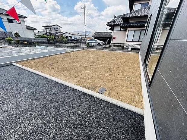 日当たりの良い庭スペースです。整地された土面が広がりさまざまな用途に対応可能です。隣接する舗装部分も活用できます。開放的な雰囲気が特長です。お手入れしやすい形状も魅力となっています。