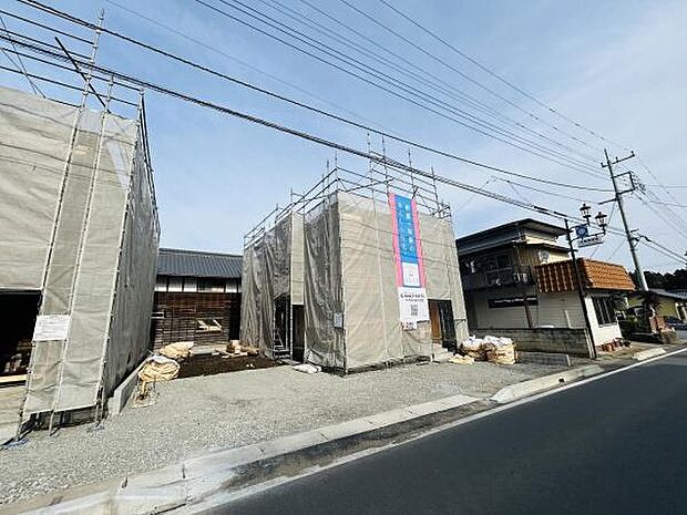 建築中の外観が確認できる写真です。周囲には住宅が立ち並び落ち着いた雰囲気です。前面道路は整備されており車の出入りもスムーズです。敷地は広めに確保され資材などもきれいに整理されています。