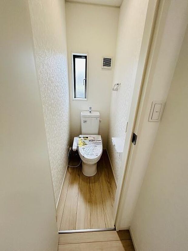 清潔感のあるシンプルなトイレ空間です。縦長の窓が設けられており自然光が入ります。壁や床の配色も明るく圧迫感を感じにくいデザインです。換気設備も設置されています。