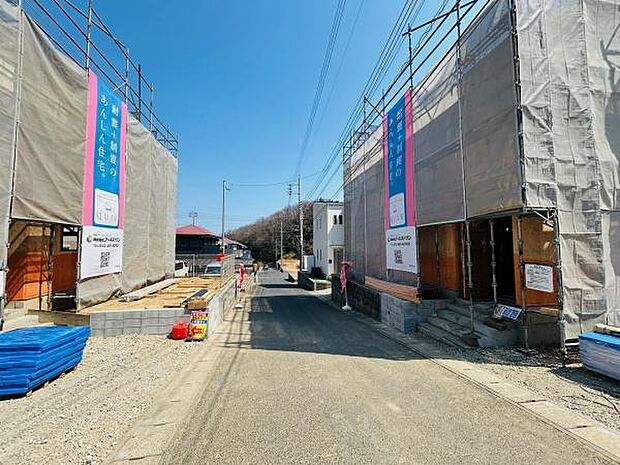 現地は前面道路がゆったりしており工事中の建物が整然と並ぶ様子が印象的です。周囲には住宅が点在し穏やかな雰囲気の街並みが広がっています。道路には電柱や配線も整備され日当たりも良好です。
