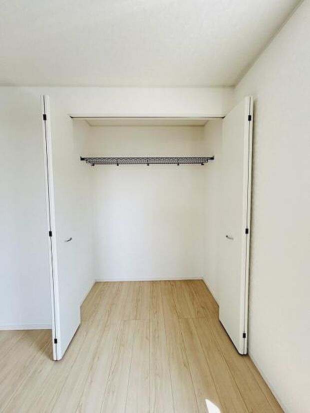 シンプルなデザインの収納スペースでお部屋がすっきりと見えます。観音開きの扉は荷物の出し入れもスムーズです。ハンガーパイプ付きで衣類を掛けて管理できます。ナチュラルな床材と明るい色合いが印象的です。