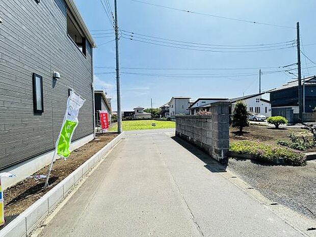 前面道路が幅広く車の出入りもスムーズに行えます。周辺には住宅が建ち並び落ち着いた環境です。道路沿いは整備されており住まいのアプローチも快適です。開放感のある現地写真となっています。