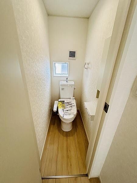 明るい空間が広がるトイレです。小窓が設けられており採光と換気も可能です。床材が印象的で清潔感のある仕様となっています。壁やドアの色合いもシンプルで落ち着いた雰囲気です。