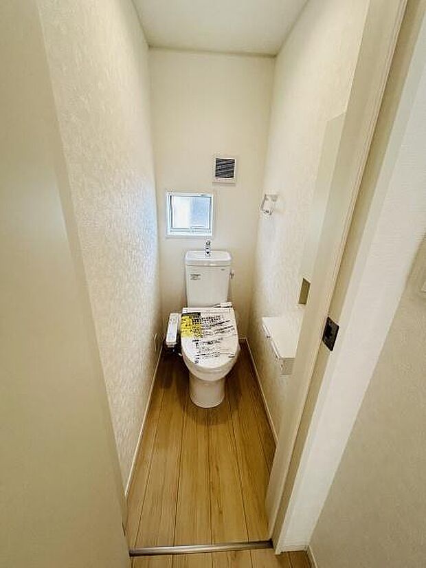 明るい空間が広がるトイレです。小窓が設けられており採光と換気も可能です。床材が印象的で清潔感のある仕様となっています。壁やドアの色合いもシンプルで落ち着いた雰囲気です。