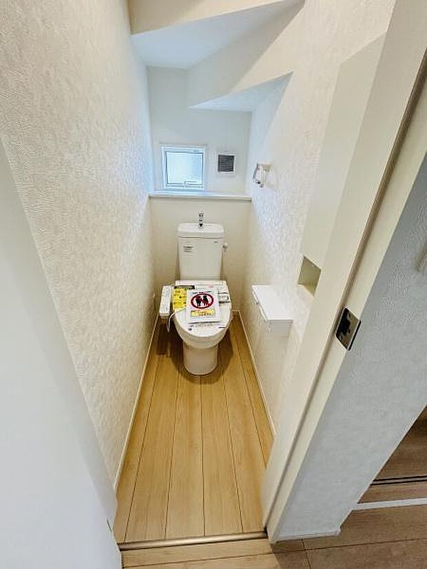 明るい窓付きのトイレです。スペースを有効活用した設計で清潔感が漂います。手洗いカウンターも設置され使い勝手に配慮されています。収納スペースも備わっております。