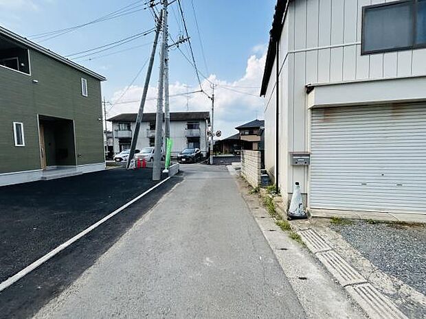 現地前面道路は舗装されており落ち着いた周辺環境が感じられます。通行量も少なく周囲の住宅とも調和した雰囲気です。敷地へのアクセスも分かりやすい立地です。道路幅も車の通行に十分な広さとなっています。