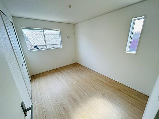 明るい光が差し込む洋室です。シンプルな内装でさまざまな使い方が可能です。床は木目調で落ち着いた雰囲気を演出しています。収納スペースも設けられています。