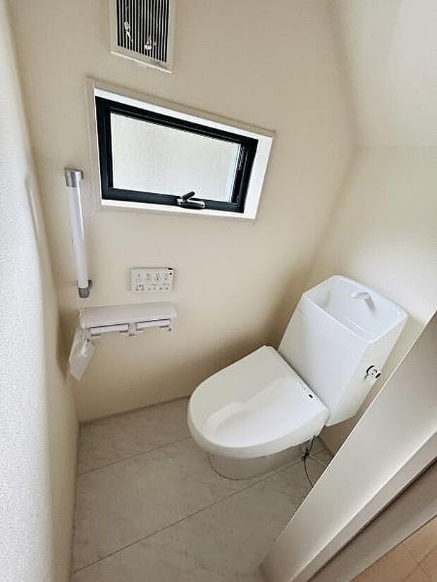 コンパクトな空間でお手入れがしやすいトイレです。手すりが設置されておりサポートが充実しています。窓付きで換気もしやすく清潔感が感じられます。壁付けのリモコンで操作もスムーズです。