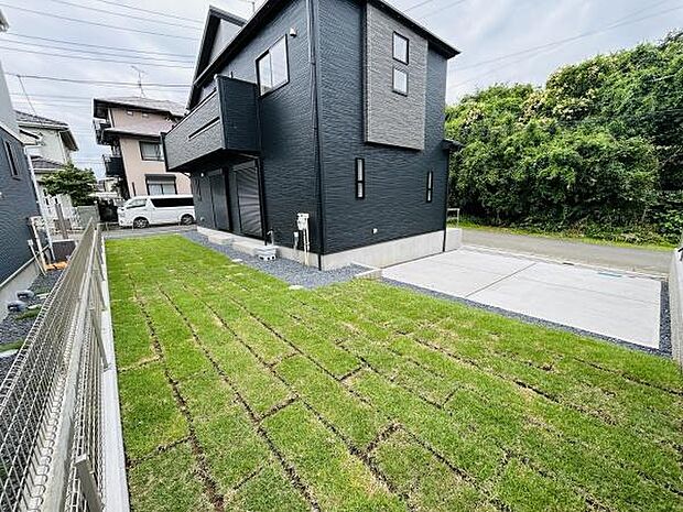 手入れの行き届いた芝生が広がる庭は住まいの外観を引き立てます。道路側への視界も確保された立地で解放感のある空間です。周囲の緑との調和が感じられる一角です。
