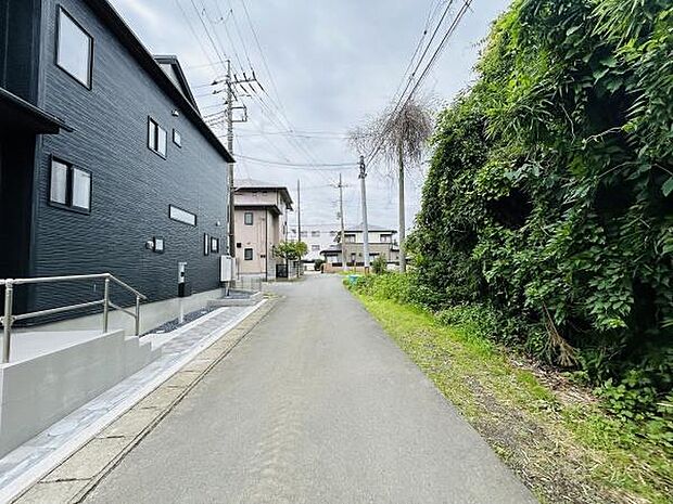 前面道路は舗装されており車の出入りがしやすい印象です。道路沿いには緑が多く住宅街ならではの静かな雰囲気が感じられます。周囲に建物が整然と並んでおり住環境が整っていることがうかがえます。