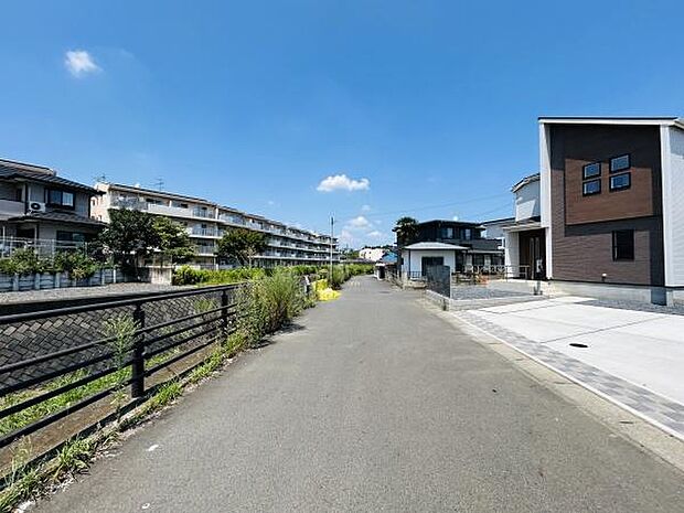 前面道路は幅員があり車の出し入れもスムーズに行えます。歩道も整備されており住環境が保たれています。周辺に住宅やマンションが立ち並び落ち着いた雰囲気が感じられます。空が広く開放感があります。