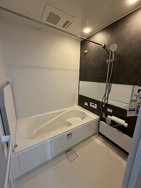 浴室の壁面には落ち着いた色合いが採用され空間全体がすっきりとまとめられています。広々とした浴槽でゆったりとした時間を過ごせます。シャワーやミラー棚も設置されていて利便性があります。