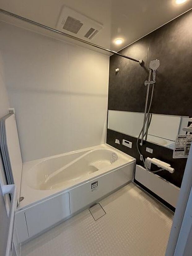 浴室の壁面には落ち着いた色合いが採用され空間全体がすっきりとまとめられています。広々とした浴槽でゆったりとした時間を過ごせます。シャワーやミラー棚も設置されていて利便性があります。