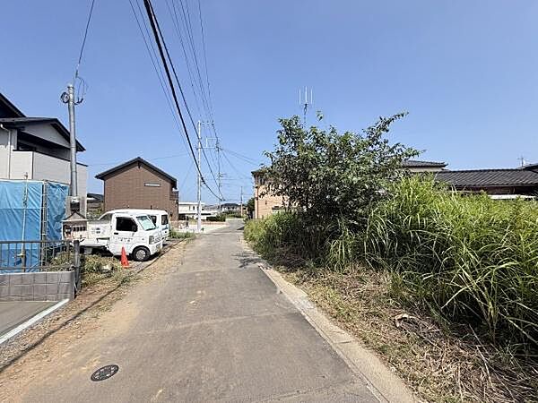 前面道路はゆったりとした幅員で車の出入りがしやすい環境です。周辺には住宅が建ち並び落ち着いた雰囲気が感じられます。道路沿いの植栽も整備されており現地の様子がしっかり確認できます。