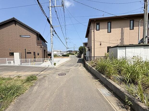 前面道路は幅員があり車の通行がしやすそうです。周辺には住居が並び落ち着いた印象があります。道路は舗装されており整った街並みが広がっています。電柱も道路沿いに並び景観が整っています。