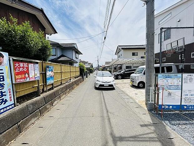 前面道路は舗装されており車両の通行も可能です。周囲は住宅が立ち並び落ち着いた雰囲気が感じられます。現地敷地周辺には生活に便利な設備も整っています。道路幅は車の移動に十分な広さがあります。