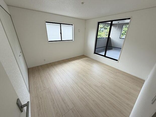 大きな窓から自然光が差し込む明るい寝室です。ベランダに面したガラス戸が開放感を与えます。清潔感のあるフローリングが魅力的です。シンプルな内装でコーディネートがしやすい空間です。