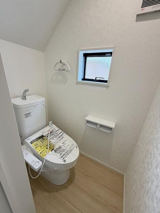 コンパクトな空間に設計されたトイレです。小窓が設けられており自然光を取り入れることができます。床材は明るい色合いで清潔感を感じられます。最新の機能付き便座が設置されています。