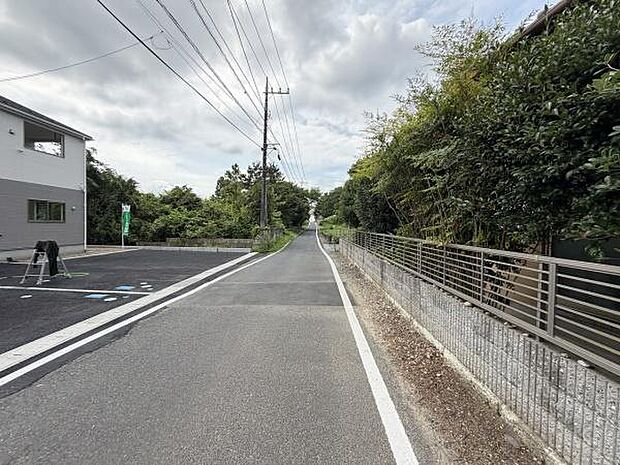 現地前面道路は直線的で見通しが良い環境です。道路幅もゆとりがあり車の出入りがしやすい印象です。周囲には緑が多く開放感を感じるロケーションです。敷地の周辺はフェンスでしっかり区切られています。