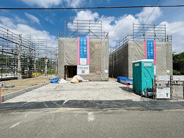 現在建築中の物件で外観や足場建築の進捗を確認できます。広々とした前面スペースがあり資材や設備も整然と配置されています。青空の下で明るい雰囲気が感じられます。現場の管理体制も見受けられます。