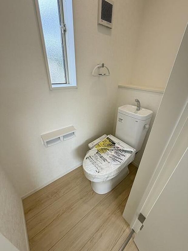 トイレに窓があり採光と換気の両方が確保されています。白を基調とした空間で清潔感があります。ペーパーホルダーや棚も設置されていて使い勝手が良い印象です。