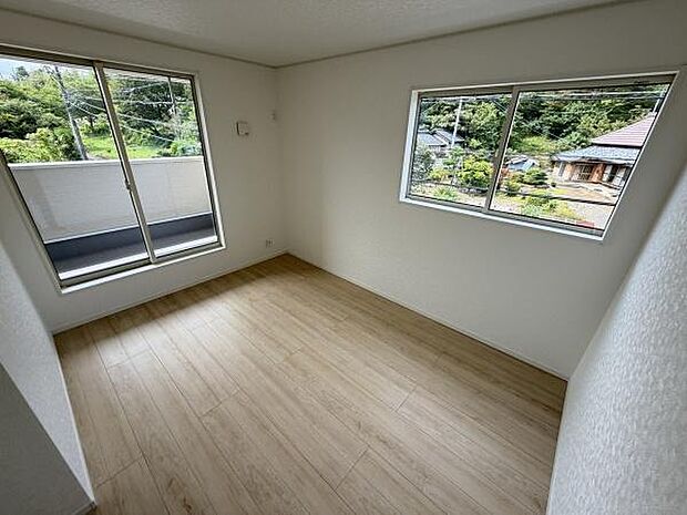 大きな窓から自然の景色が楽しめる洋室です。明るい空間が広がり清潔感のあるフローリングが魅力です。二面採光で開放感のある一室になっています。各種インテリアとも調和しやすいシンプルなデザインです。