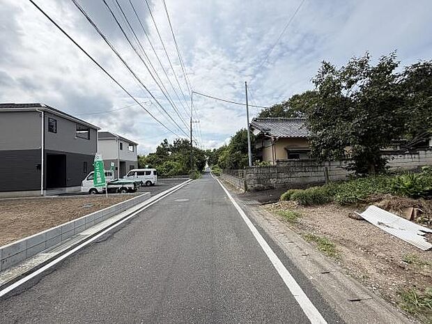 前面道路は幅員が広く車の出入りもしやすい印象です。周囲には住宅が点在しており閑静な雰囲気です。道沿いには電線や緑も見られ周囲の環境が分かりやすい一枚です。現地の様子が一目でわかります。