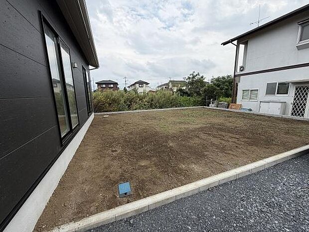 ゆったりとしたスペースが広がる庭はシンプルながらも開放感が特徴です。周囲は住宅地で落ち着いた環境が感じられます。平坦で整った地面が使いやすい印象を与えています。