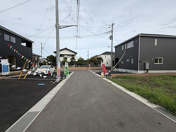 現地は広々とした前面道路に面しており車の出入りがしやすい環境です。道路沿いには新しい住宅が並び周囲も整備されています。電柱や標識も設置されており周辺のインフラも充実しています。