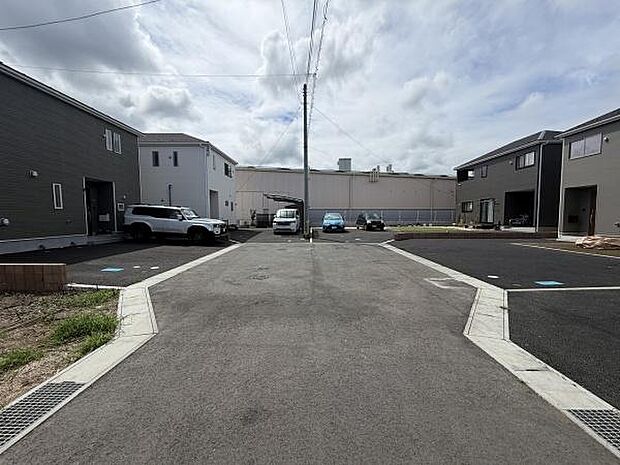 前面道路がゆったりと確保されており車の出し入れもスムーズに行えます。周囲には新しい建物が並び落ち着いた雰囲気が感じられます。敷地内へのアクセスも簡単なつくりです。現地の様子が一目でわかる写真です。