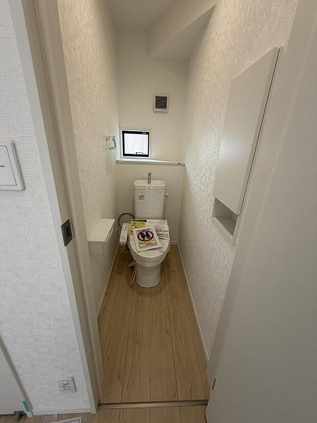 コンパクトな空間に設けられたトイレです。小窓があり自然光を取り入れやすい設計です。シンプルな内装が特徴でお手入れも簡単にできます。木目調の床材が落ち着いた雰囲気を演出します。