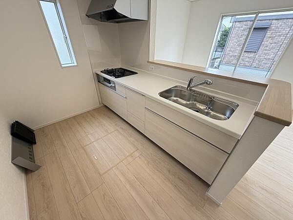 明るい色調のフローリングとシンプルなデザインが特徴のキッチンです。窓から自然光が差し込み清潔感のある空間となっています。カウンター部分が広く使い勝手を重視したレイアウトです。