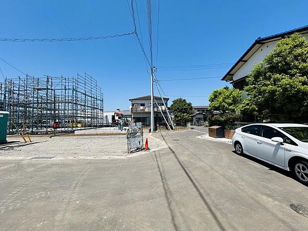 建築中の現地と前面道路の様子がよくわかります。周辺には住宅が並び落ち着いた街並みが広がっています。道路幅も十分にあり車の出し入れがしやすい環境です。現地までのアクセスも分かりやすい位置にあります。