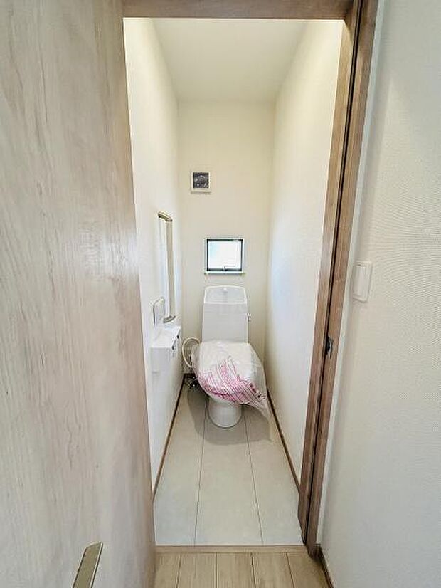 シンプルなデザインのトイレで清潔感が感じられます。窓があり自然光が差し込む明るい空間です。扉や床材にも統一感があり落ち着いた印象です。使い勝手の良い手洗いスペースも設けられています。