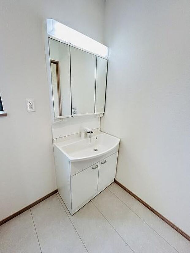 清潔感のある洗面台は収納スペースも充実しています。明るい照明付きの三面鏡が設置されており身支度がしやすい仕様です。床はお手入れしやすい素材となっています。すっきりとしたデザインが特徴です。