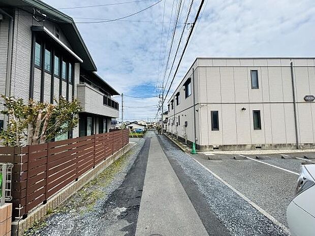 前面道路は舗装されており歩きやすい印象です。両側に住宅と駐車場が広がり見通しのよい道幅があります。周囲は落ち着いた雰囲気で整然とした街並みが魅力的です。電線も整理されていてすっきりとした景観です。
