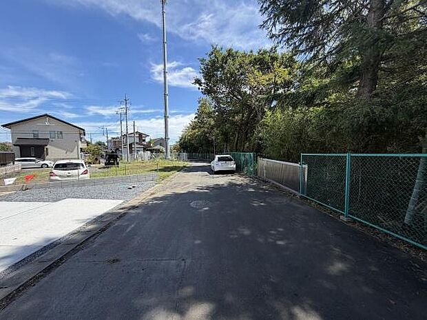 前面道路は見通しが良く落ち着いた環境が広がっています。両側にフェンスや緑があり開放感のある雰囲気です。舗装された道路が敷地までしっかりと続いており車の出入りもスムーズです。